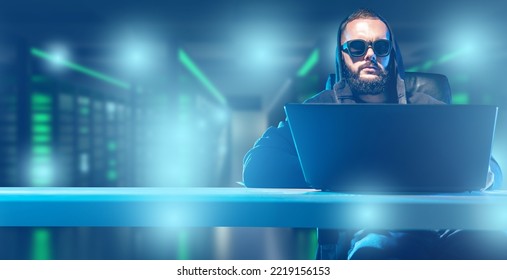 Hacker Man. Computer Hacking Specialist. Guy With Laptop Is Sitting At Table. Hacker In Server Room. Concept Of Hacking Servers With Data. Man Internet Criminal. Hacker At Work. Art Blurred