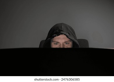 Hacker, man with laptop, hooded figure, cyber stalker, internet threat. - Powered by Shutterstock