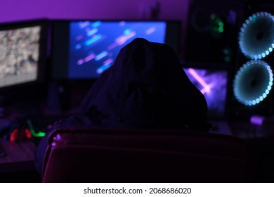 Hacker man sits with his back against the background of working computer screens