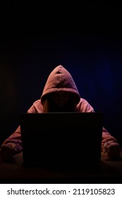 Hacker near front of computer laptop. Woman hacker in dark room background