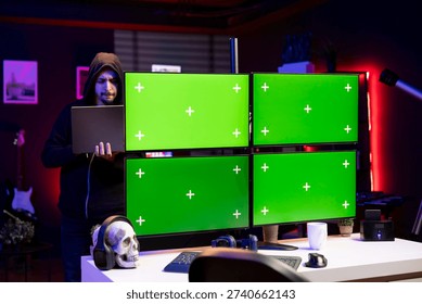 Hacker in office using laptop and exploits on isolated screen PC to break into systems and access restricted data. Man using mockup multi monitor setup VPN on dark web to sell sensitive information