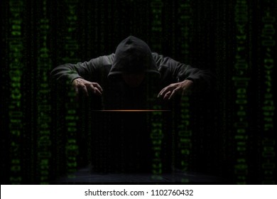 hacker over a screen with green binary code. Crime and Information Theft and Computers