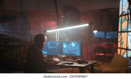 Hacker running phishing software on computer in criminals den with graffiti sprayed on walls. Cybercriminal doing malware programming in dark foggy underground base, breaching security