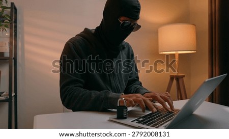 A hacker types on a laptop next to a padlock, highlighting the ongoing battle between online security and cyber threats. The scene shows hacking, digital risk, privacy, and cyber defense.
