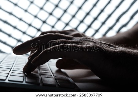 Hacker typing on a keyboard behind bars in darkness, illustrating themes of cyber crime, internet fraud, data breaches, and the looming threats to online security and privacy