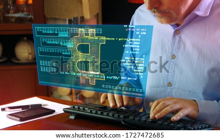 Hacker typing on the keyboard and Bitcoin mining on hologram screen on desk. Digital crypto currency, cyber money and digital banking concept.