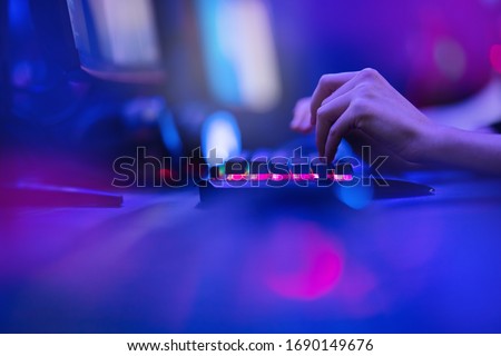 Hacker uses keyboard, shakes buttons with fingers to crack password. Internet security concept, cyber attack. Neon blue color.