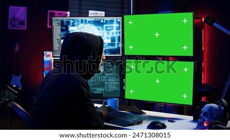 Hacker using AI and green screen computer monitors to produce malicious malware corrupt company data. Evil man working on mockup desktop PC using artificial intelligence, infecting systems, camera B