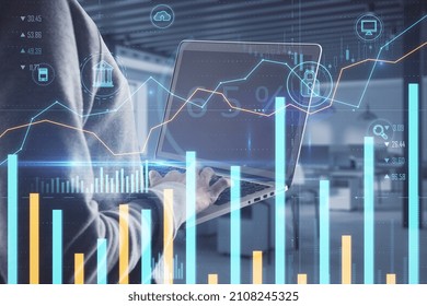 Hacker using laptop with creative glowing business chart on blurry office background. Online banking, safety, hacking and finance concept. Double exposure