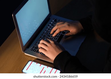 Hacker using laptop at table, closeup