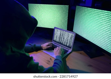 Hacker working with computers at wooden table indoors. Cyber attack