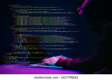 Hacker working with laptop in dark room with digital interface around. Image with glitch effect.