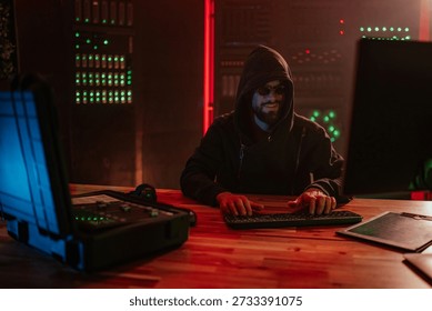 Hacker working on computer in dark server room, engaged in cybercrime activity and digital data breach