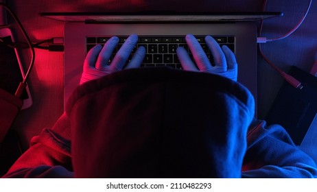 Hacker Working On Laptop At Night . Hands Of A Hacker In Rubber Gloves