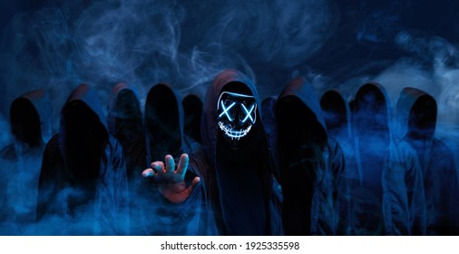 Hackers Army. Dangerous Hooded Group Of Hackers. Internet, Cyber Crime, Cyber Attack, System Breaking And Malware Concept. Dark Face. Anonymous. Abstract Smoke Moves On Black Background.