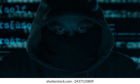 Hacker's Gaze Amidst Digital Chaos. Hooded figure with a masked face, program code in the background in a dark setting.