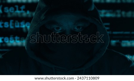 Hacker's Gaze Amidst Digital Chaos. Hooded figure with a masked face, program code in the background in a dark setting.