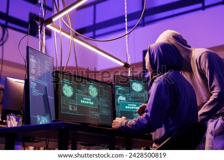 Hackers getting access granted while breaking into online server on computer. Two smiling criminals happy after successful ddos attack on website in abandoned warehouse at night