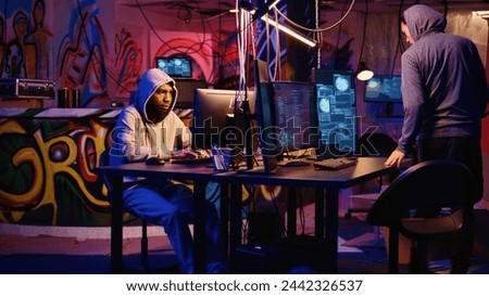 Hackers in secret base talking about technical knowhow details before using bugs and exploits to break into computer systems and access valuable data, bypassing firewalls, zoom out shot