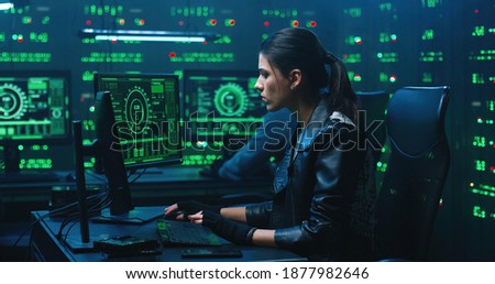 Hackers using computer for organizing massive data breach attack on corporate servers. Secret location surrounded by displays, servers and cables.