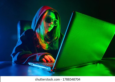 Hacking. Hacker near the laptop. Girl makes a hacker attack. Internet hacking. Concept - a member of a hacker group. Geek in a dark room. Concept - computer geek. Woman in front of a computer.
