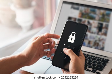 Hacking a Phishing mobile phone with a password to access a smartphone, security threats online, and fraud. A young man with a cell phone and laptop is secure in his bank account.