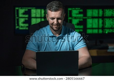 Hacking programmer uses laptop computer. Hacking programmer writes code at night. Hacking programmer monitors server system. Hacking programmer creates cyber threat.
