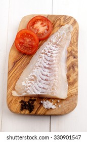 Haddock Fillet With Tomato, Pepper And Coarse Salt On A Wooden Board