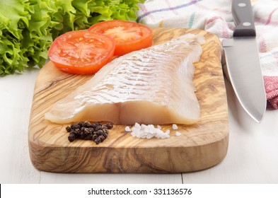 Haddock Fillet With Tomato, Pepper And Coarse Salt On A Wooden Board