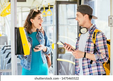 Hadsome student male traveler with headphones and smartphone in hand asking for help woman with backpack at tram. Communication, acquaintance, friendship concept. Sun glare effect - Shutterstock ID 1475465522