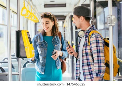 Hadsome student male traveler with headphones and smartphone in hand asking for help woman with backpack at tram. Communication, acquaintance, friendship concept. Sun glare effect - Shutterstock ID 1475465525