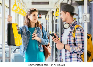Hadsome student male traveler with headphones and smartphone in hand asking for help woman with backpack at tram. Communication, acquaintance, friendship concept. Sun glare effect - Shutterstock ID 1475465528