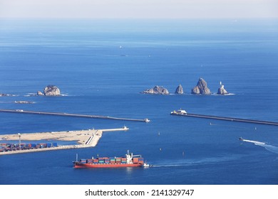 Haeundae-gu, Busan, South Korea - January 14, 2022: Aerial view of a container ship sailing on the sea against Oryukdo Island and breakwater at Busan Port
