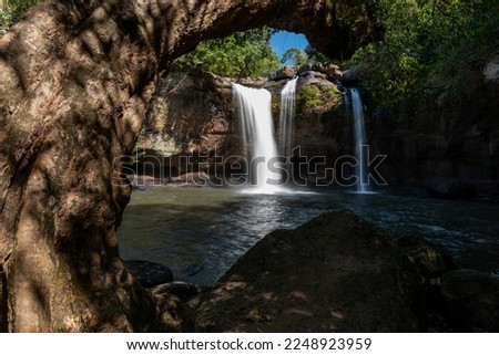 Haew Suwat Waterfall photo. Khao Yai uses large trees as a foreground to create a frame leading the eye towards the waterfall and the water.