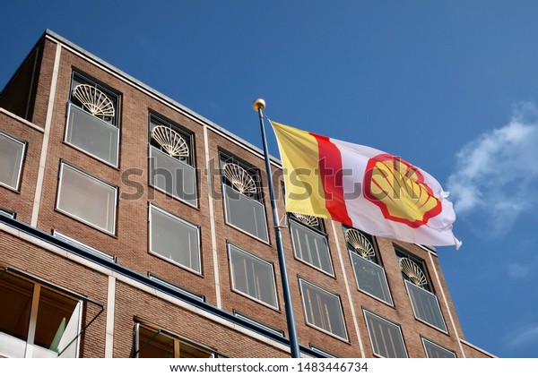 THE HAGUE - AUGUST 19, 2019: ROYAL\
DUTCH SHELL company flag and logo at headquarters\
building