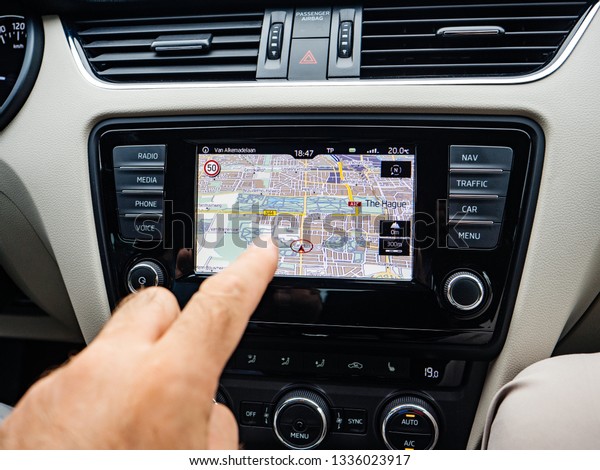 THE HAGUE, NETHERLANDS - AUG 19, 2018: Crop shot of\
male finger pointing at GPS tablet inside of car while navigating\
in city of Hague
