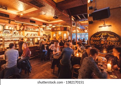 HAGUE, THE NETHERLANDS: People Drinking And Eating Snacks Inside Old Pub With Beer Taps, Vintage Furniture And Decorations On April 6, 2018. Hague Is One Of Major Cities Hosting The United Nations