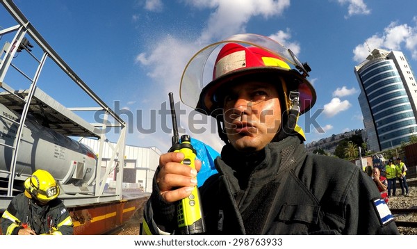 HAIFA,\
ISRAEL - JUNE 30, 2015: Firefighter from Northern Israel with\
protective gear and walky talky during simulation drill of leak of\
Bromine chemical in a container car of\
train.