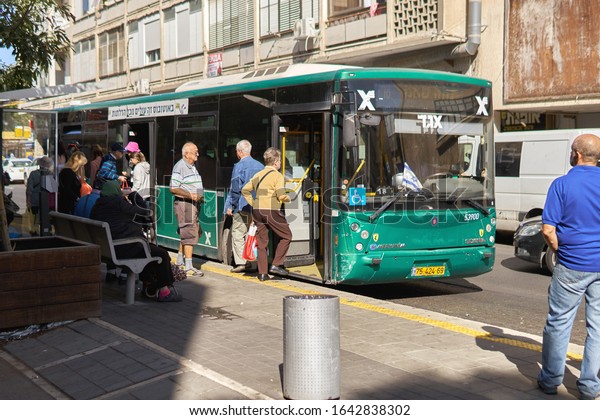 Haifa, ISRAEL-\
November 20, 2019. People get on the bus at the bus stop on the\
Haifa street on sunny november\
day