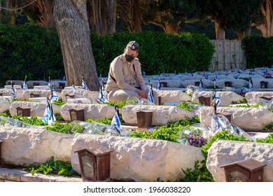 HAIFA MILITARY CEMETERY, ISRAEL -  APRIL 14, 2021. Soldier sitting near  other soldiers graves on Memorial Day for the Fallen Soldiers of Israel and Victims of Terrorism.
