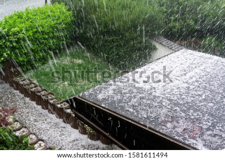 Hail falls on a house roof during a hailstorm