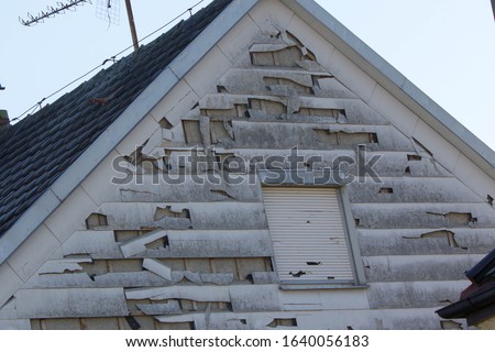 hail and storm damage at house wall, stormy weather, Holes in exterior siding in home from damage by hail storm , climate change, danger