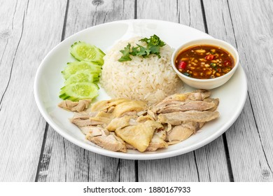 Hainanese chicken rice, or "Khao Mun Kai" in Thai name, a dish of poached chicken and oily rice, served with chilli sauce and cucumber. - Shutterstock ID 1880167933