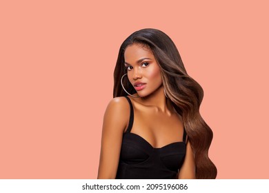 Hair. Beauty Portrait of a black woman with long curly brown hair. Makeup. African American model close up. Closeup portrait woman hair care copy space. Isolated. Studio shot. Peach background 