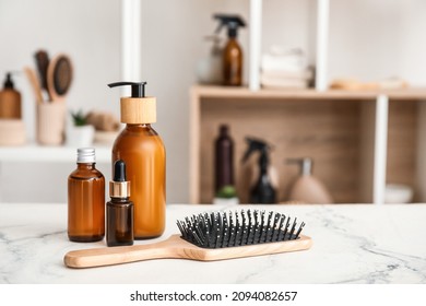 Hair brush and bottles of cosmetic products on table in room