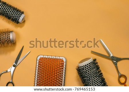 Hair brushes and scissors on the orange background