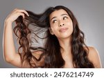 Hair care, beauty and woman in studio with salon, shiny and healthy treatment for confidence. Wellness, soft and female person with grooming routine for long and wavy hairstyle by gray background.