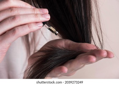 Hair care concept. Woman applying dropper with oil or serum essence on ends hair. Close up - Shutterstock ID 2039273249