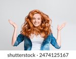 Hair Care. Portrait of cheerful redhead girl with flying curly hair, laughing at camera, having fun on gray background.