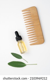Hair care set. Wooden comb, hair oil. White background, top view.